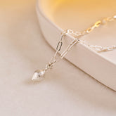 A silver miniature lemon jewellery charm on a silver paper clip chain.